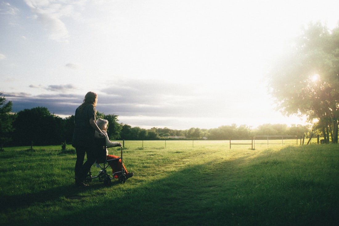 A caregiver walking with a senior client outdoors at sunset
